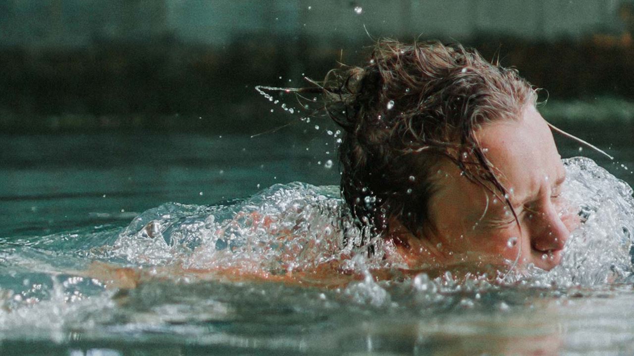 Boy swimming in a lake, with head emerging from the surface of the water