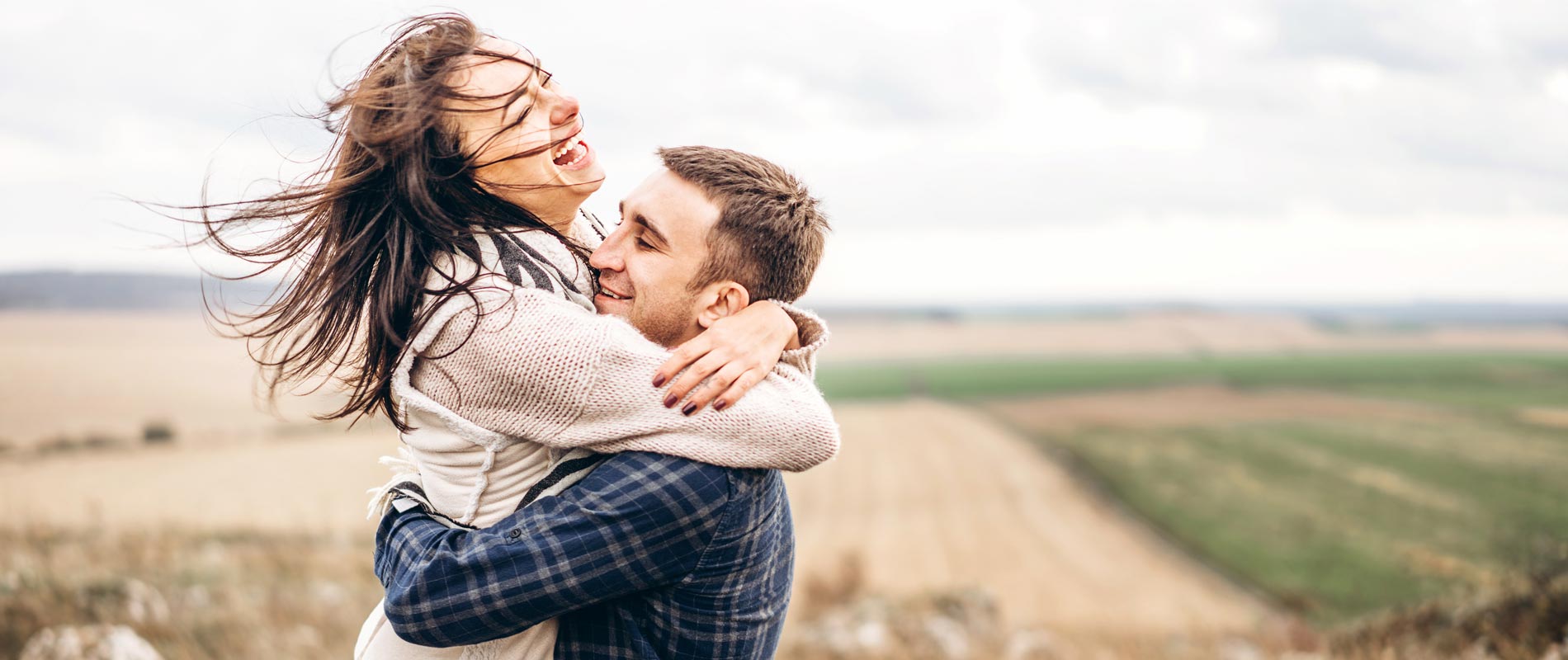 a happy couple embrace in a field showing natures beauty