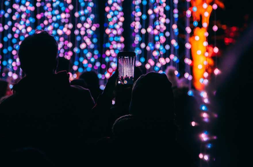 Illuminated trails of purple and blue lights with the shadow of people in the forground around Blenheim Palace