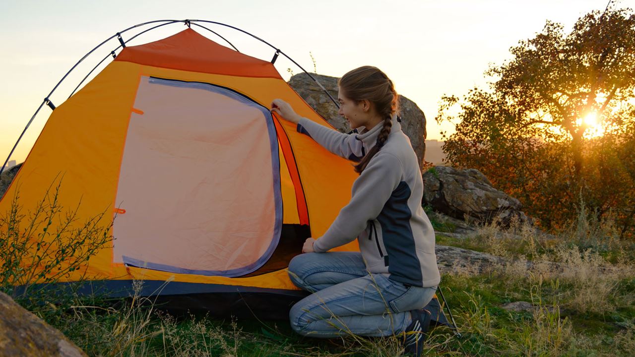 Girl putting up a tent surrounded by nature