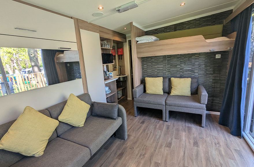 The interior of a glamping pod at Abbey Wood campsite, London. Looking at the double sofas and kitchenette area.