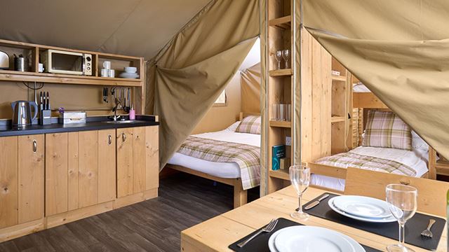 Interior of a safari tent shwoing dining table and two bedrooms