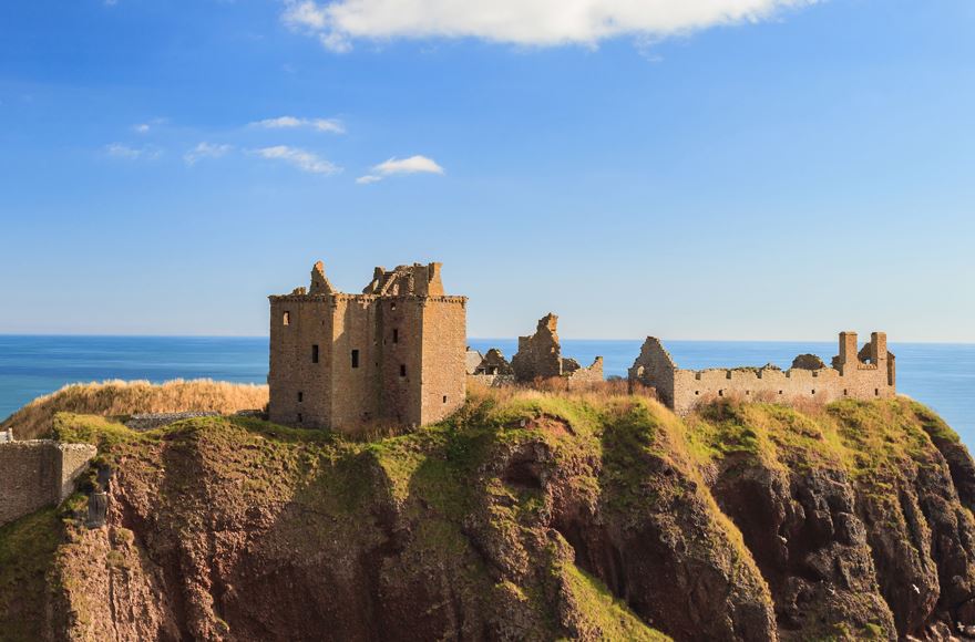 Dunnottar Castle Ruins on cliff top against a calm blue sky 