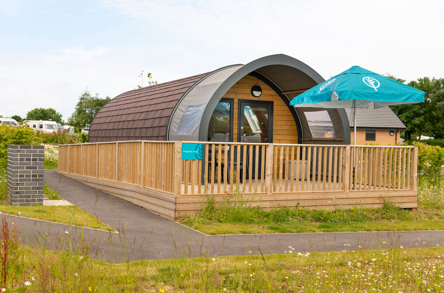 Glamping cabin featuring a deck and umbrella, nestled in a serene outdoor setting