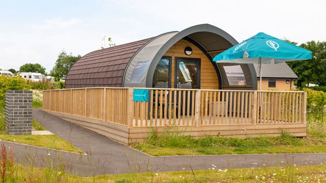 Glamping cabin featuring a deck and umbrella, nestled in a serene outdoor setting