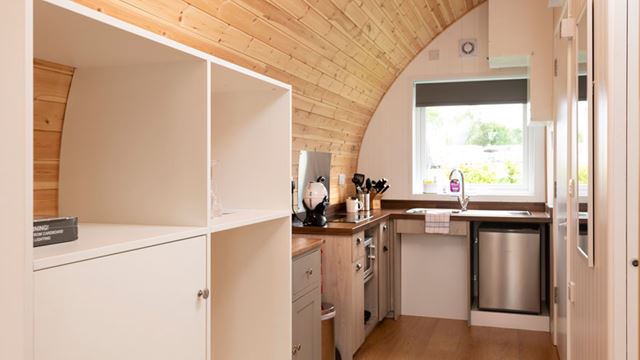 A compact kitchen featuring a sink, fridge and shelving