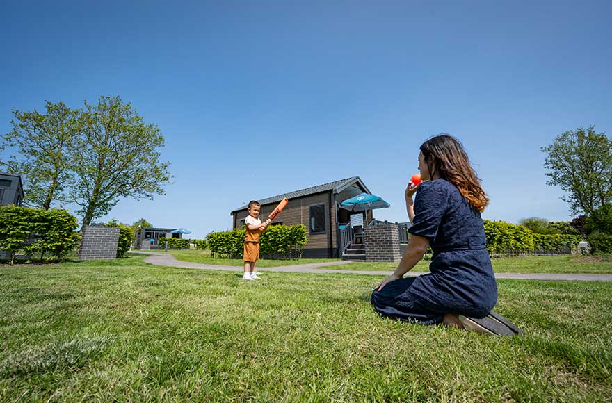 mother and child having fun together outdoors in the grass infront of their glamping cabin