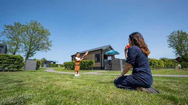 mother and child having fun together outdoors in the grass infront of their glamping cabin