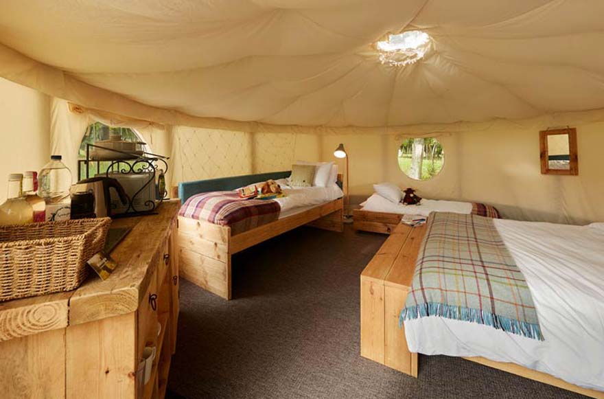 Interior of a canvas yurt with two beds and a table inside