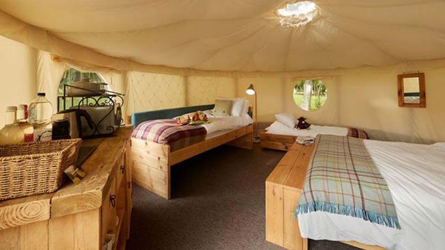 Interior of a canvas yurt with two beds and a table inside