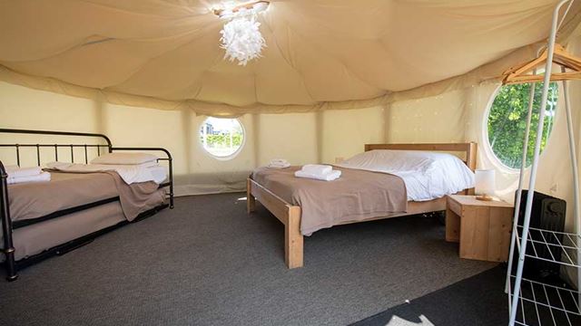 Cozy canvas yurt setup with a bed and sofabed, ideal for a camping trip in the wilderness