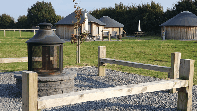 Wooden yurts surrounding a communal fire pit area at Daleacres Experience Freedom campsite.