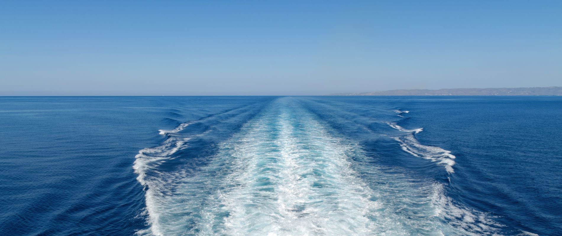 A boat making its way across the ocean, with tranquil waters and a picturesque horizon in the background