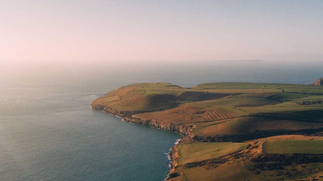 the dancing ledge in Swanage with sweeping green fields surrounded by a calm sea