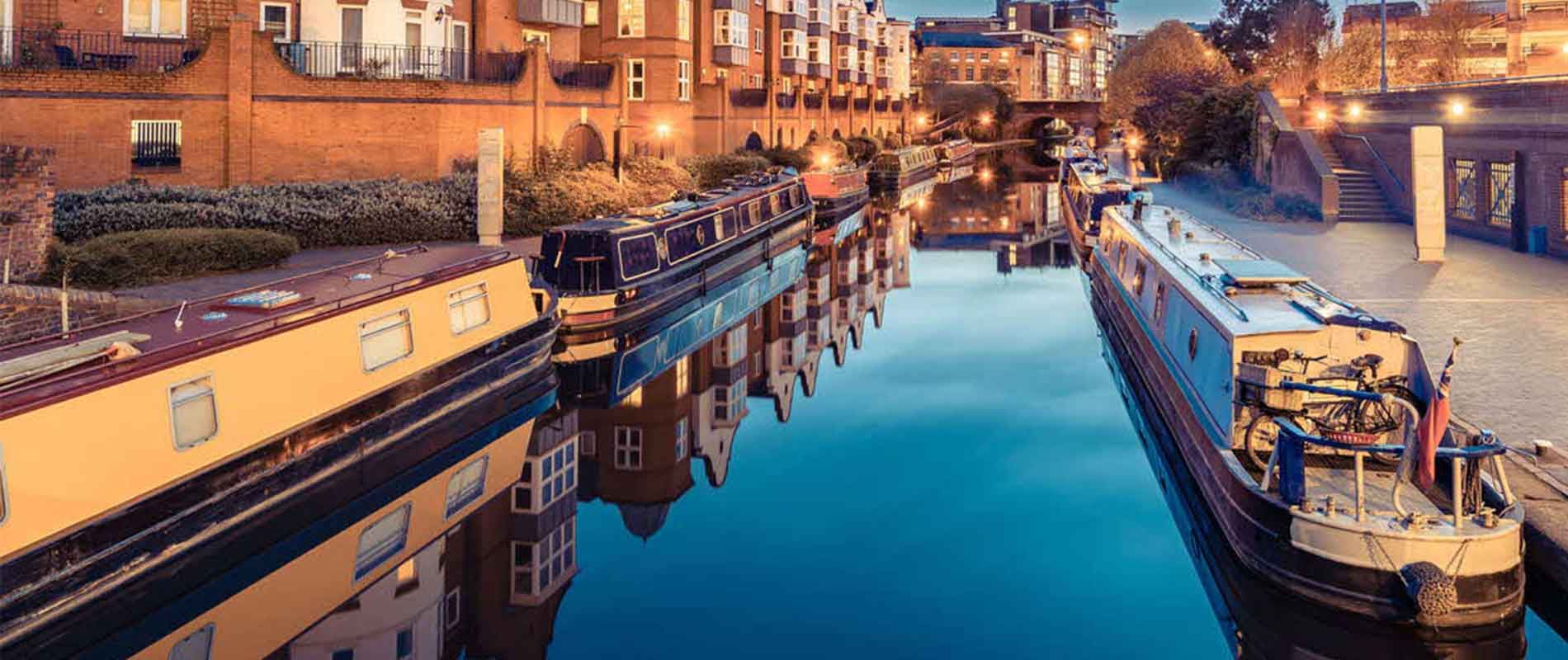 canal lined with long boats at dusk