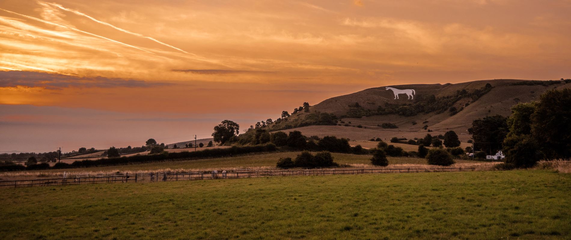 the Wiltshire white horse etched into the fields under a dusty orange sky