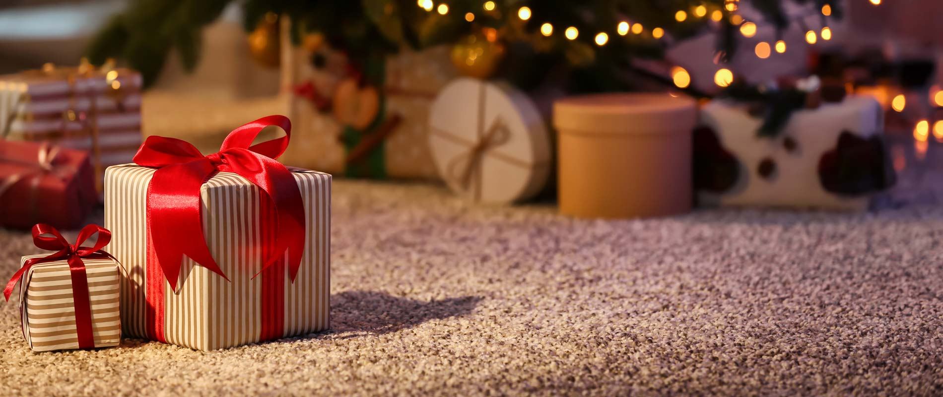 A wrapped present with a bow underneath a chistmas tree 
