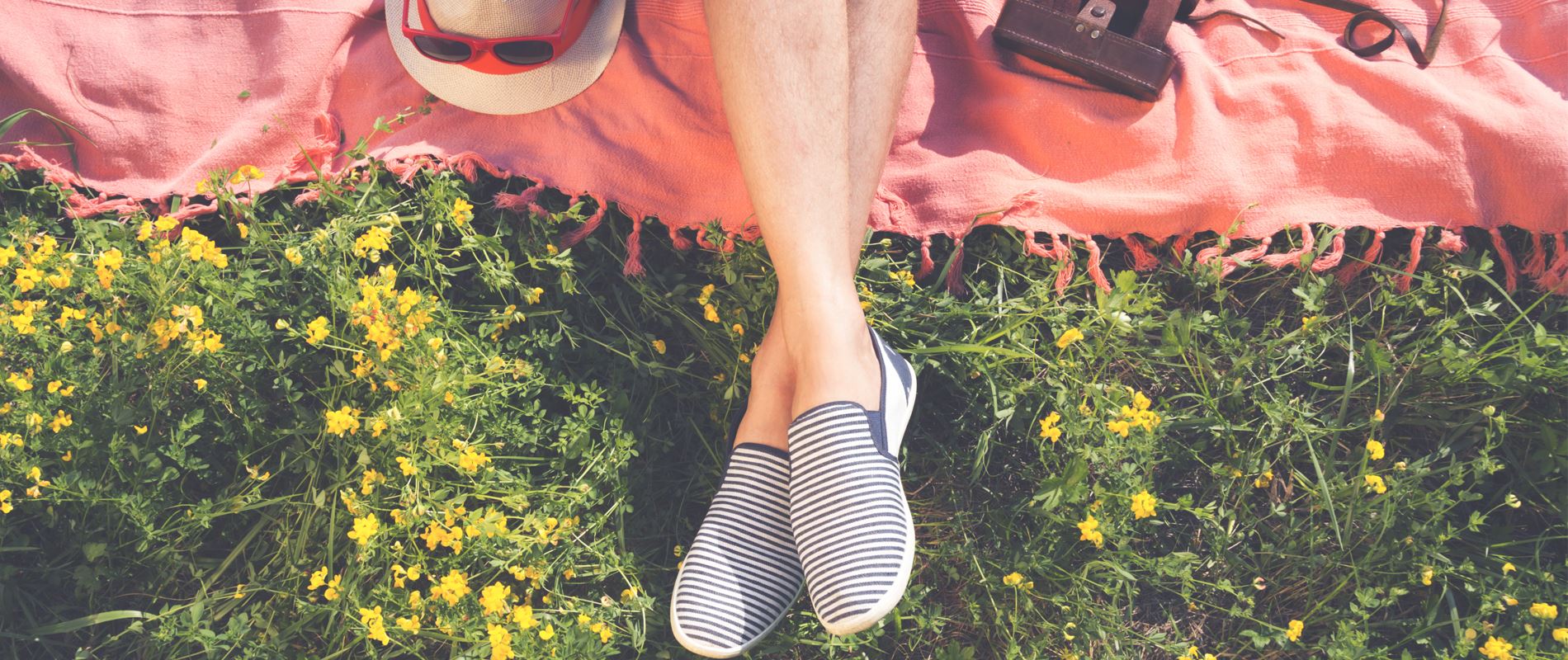 View on mans legs relaxing on a blanket in a field