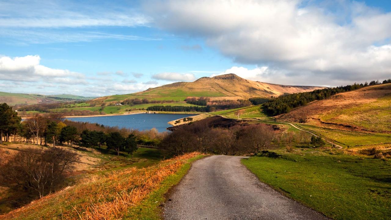 View of a winding road, mountains and lakes in the Peak District.