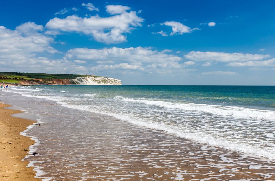 Sandown beach with gentle waves lapping at the shore under a clear blue sky, inviting relaxation and tranquility