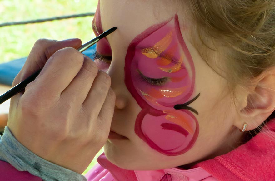 Little girl having a pink butterfly painted on her face