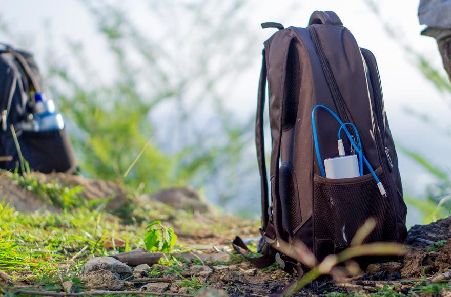 Backpack on woodland floor with battery pack and survival kit
