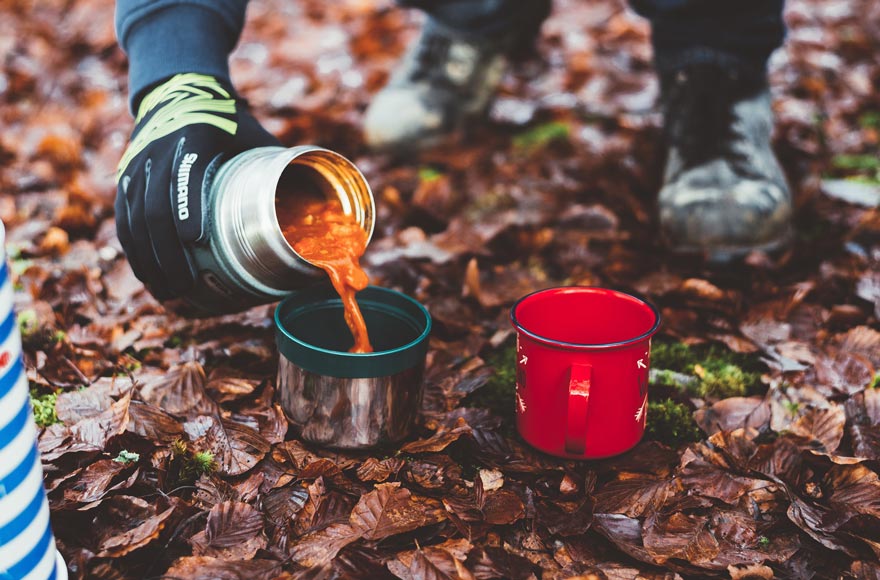 Camper pouring a pre-prepared soup into a metal canister