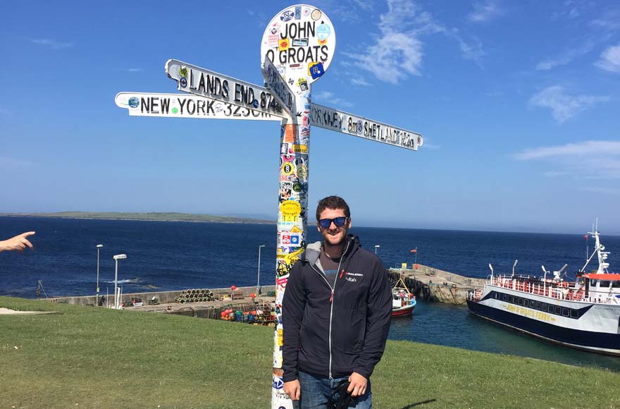 Signpost by John O'Groats with ships in the dock