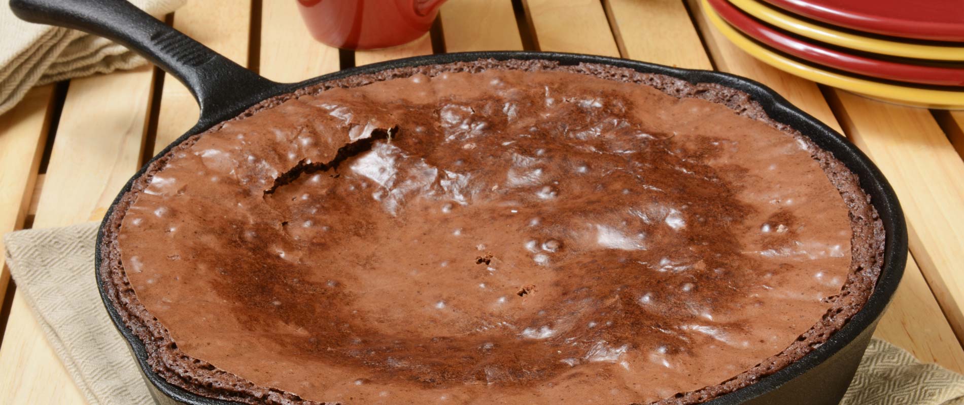 Chocolate brownie cooked in an iron skillet on a wooden dining table