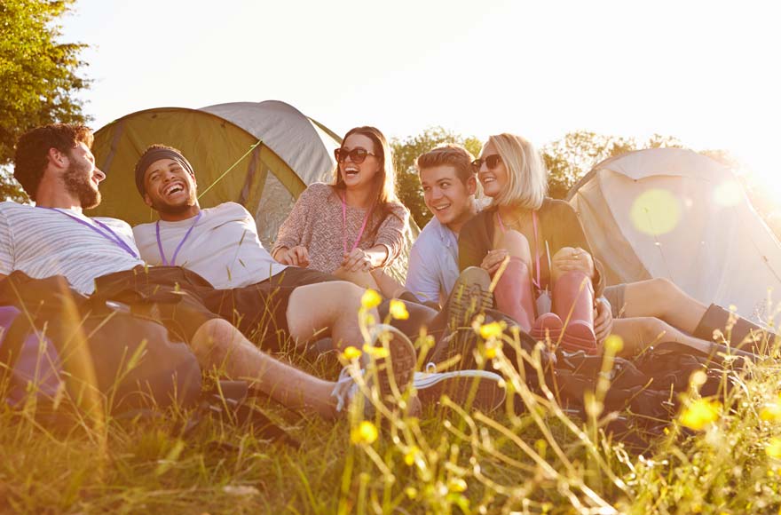 Group of friends sitting outside tent, laughing and joking